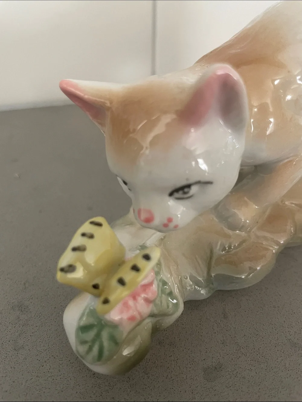 Vintage porcelain cat figurine playing with a butterfly.